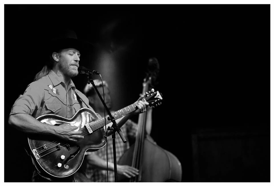Aaron Jennings singing and playing guitar onstage with an upright bassist.