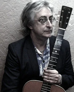 Richie Reinholdt holding an acoustic guitar.