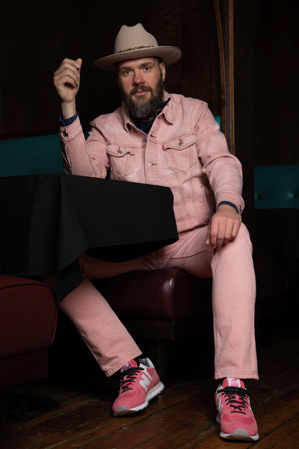 Travis Yost seated indoors wearing a pink suit and cowboy hat.