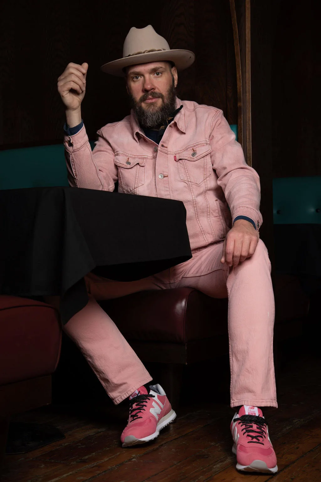 Travis Yost seated indoors wearing a pink suit and cowboy hat.