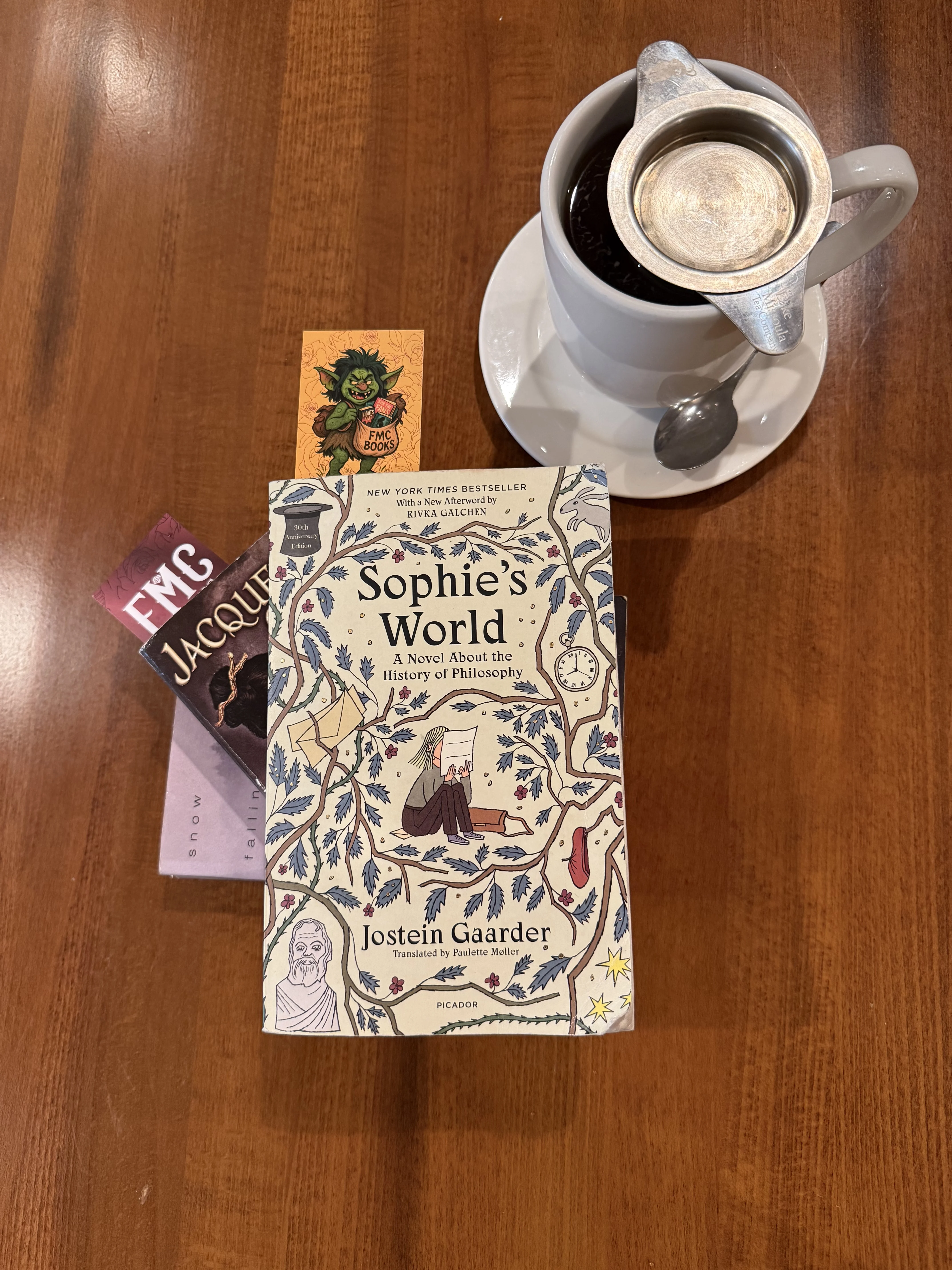 Books and a cup of tea on a wooden table at Sumac Cafe.